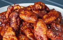 A close up of some chicken wings in sauce
